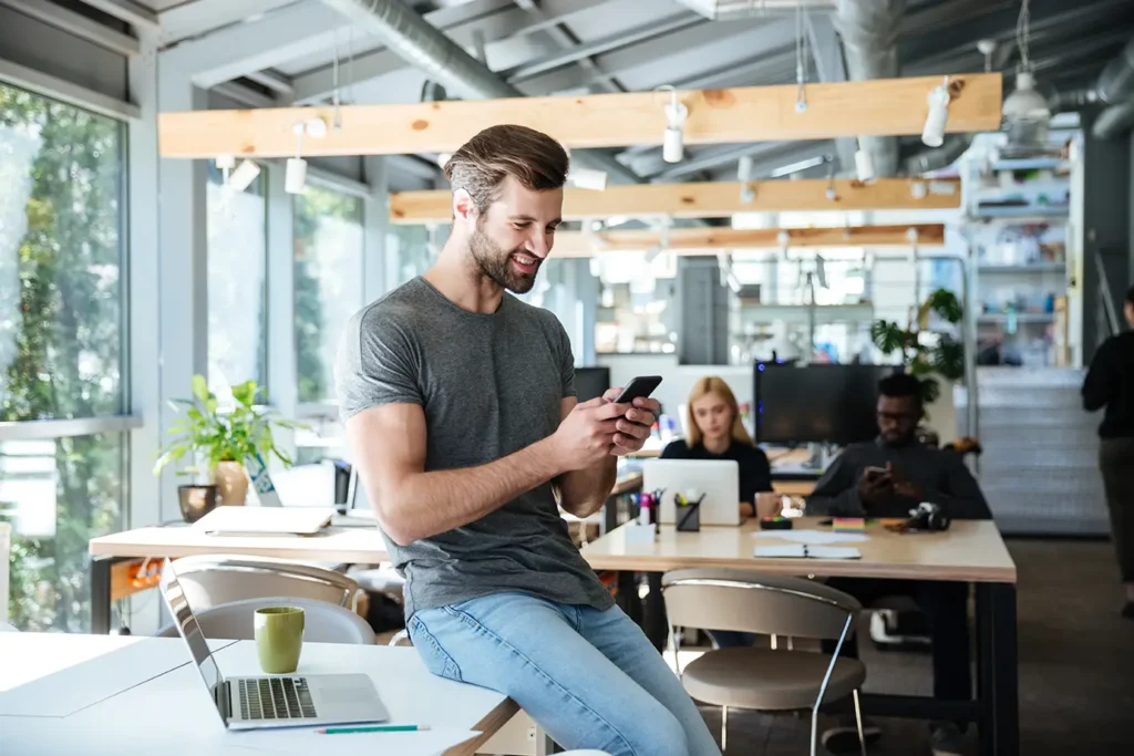 Joven sentado en la mesa de un coworking evaluando si merece la pena trabajar desde casa vs coworking